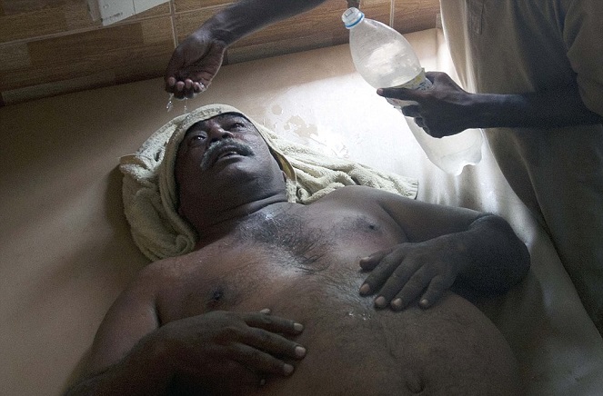 Seorang pria yang dibantu untuk mendinginkan tubuhnya [Image Source]