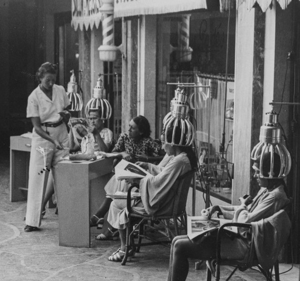 Dauerwellen im Badeanzug vor einem Friseurladen in Cannes. Photographie. 1937. Hairdresser in Cannes, France. Photography. 1937