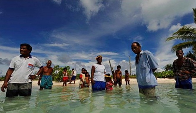 Penduduk Abaiang, Kiribati berdiri di laut tempat rumah mereka dulunya berada [Image Source]
