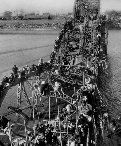 Pengungsi memanjat jembatan yang ambruk [Image Source]