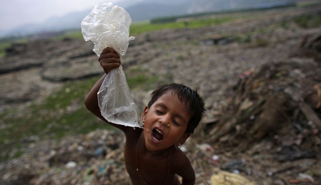 Seorang bocah minum air dari plastik [Image Source]