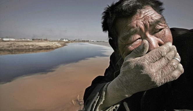Seorang kakek menutupi hidungnya karena sungai yang bau [Image Source]